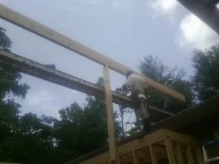 Carpenter setting a ridge beam over a new addition frame — Ice Dam Removal by Roofing Brothers in Ellendale