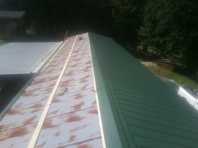 Old rusted panels beside newly installed green metal roofing — Wind Damage Roof Repair by Roofing Brothers in Ellendale