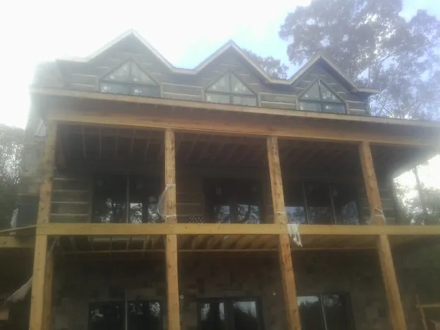 Dormers and porch framing on a large log home under construction — Roof Coating work by our crew in Ellendale