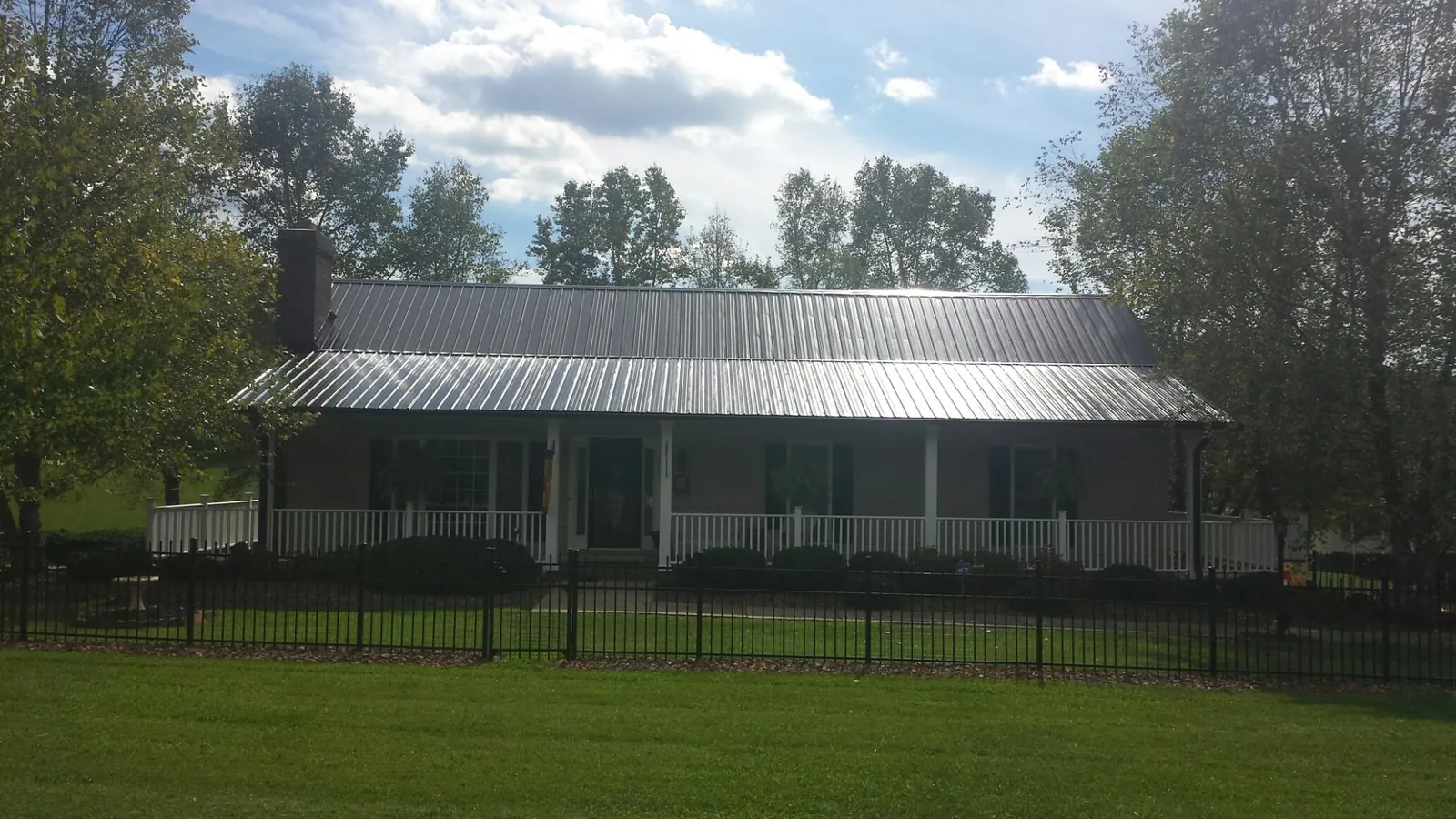 Gray metal roof on a brick ranch with a full width front porch — Gutter Guard Installation work by our crew in Ellendale