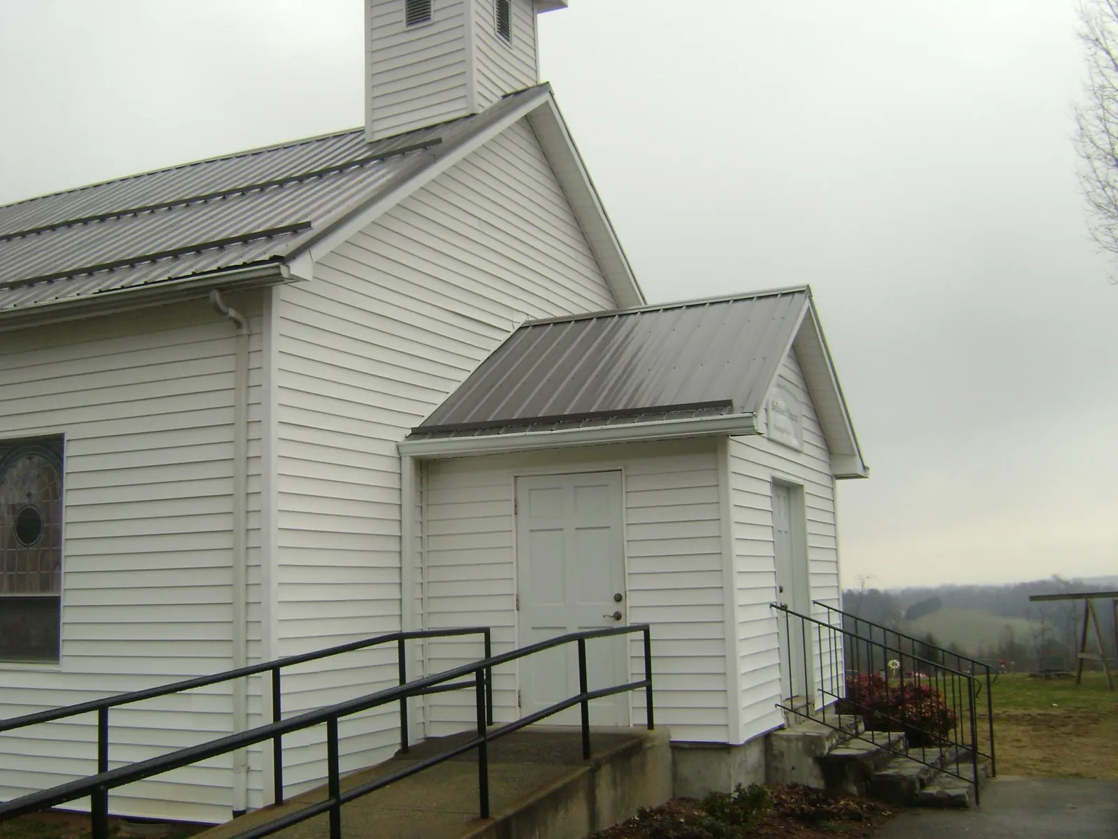 Gray metal roof on a white clapboard church with a steeple in Ellendale