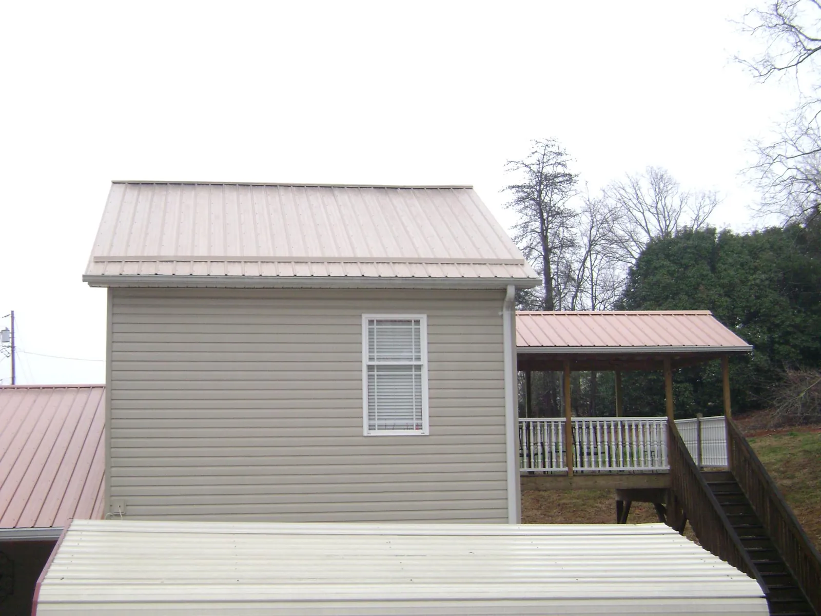 Tan metal roofs on a two story addition and attached porch, from a Roof Replacement job in Ellendale